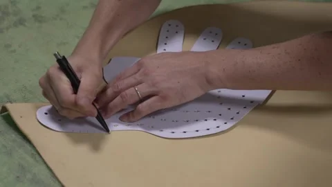 Craftsman tracing a perforated paper pattern onto leather with a pen for Stock Footage 340156113
