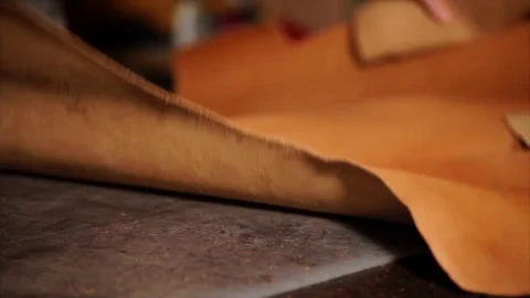 Craftsman unfolding leather sheet on working table Stock Footage 81449801