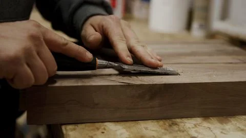 Craftsman uses a chisel on a raw piece of wood in a workshop setting Stock Photos
