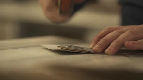 A craftsman uses a hammer and rivets to attach a metal decoration to the leather Stock Footage 266142288