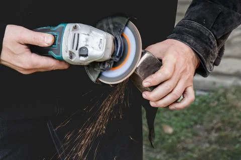 Craftsman using an angle grinder with flying sparks while shaping a metal p.. Stock Photos