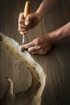 A craftsman using a chisel to carve out a deep groove in a piece of wood. Stock Photos