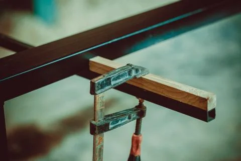 Craftsman using clamps fixate two pieces of wood and iron. The process of mak Stock Photos