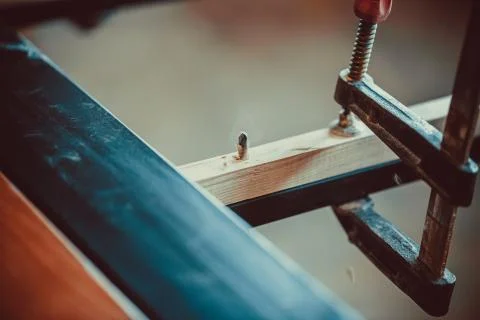 Craftsman using clamps fixate two pieces of wood and iron. The process of mak Foto stock