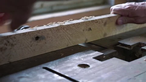 A craftsman using a hand planer on a wooden beam in a workshop, emphasizing.. Video stock 282896551