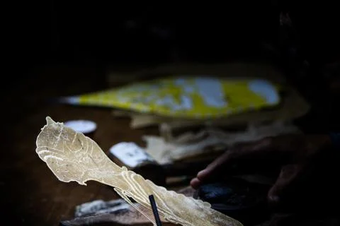 Craftsman using punch tool on raw leather shadow puppet during traditional .. Stock Photos