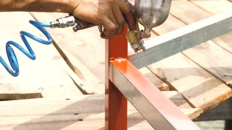 Craftsman using spray gun for applying brown paint on metal parts. Worker Stock Footage 101735851