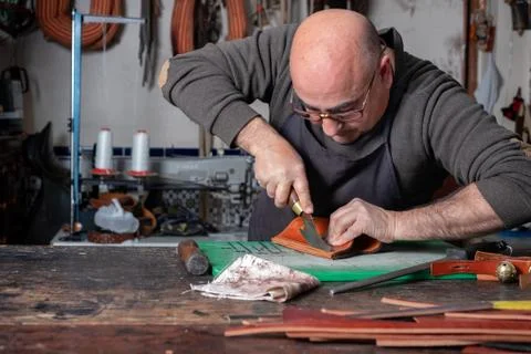 Craftsman working the leather in his small saddlery workshop Stock Photos