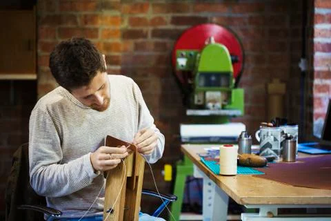 A craftsman in a workshop, threading cord or twine through a small handmade Stock Photos