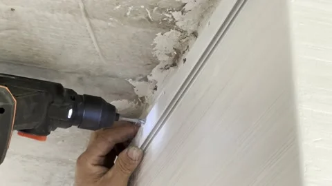 Craftsman's hands making a hole in the wall with a drill Stock Footage 219423054
