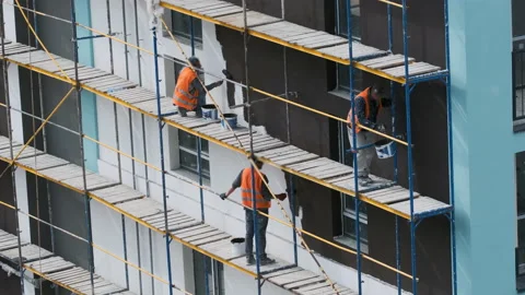 Craftsmen on the scaffolding on the construction site make the facade Stock Footage 194702863