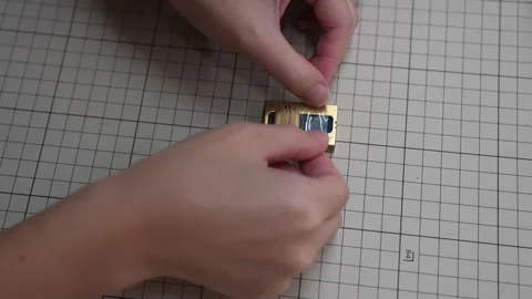 Craftsperson sets gold snap button into wallet leather with punch tool Stock Footage 339642843