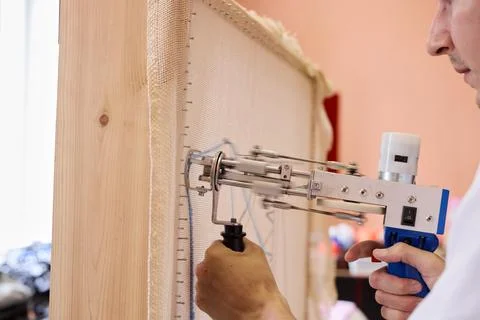 Craftsperson using stapler to secure fabric on wooden frame Stock Photos