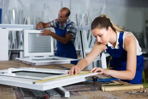 Craftswoman is checking dimensions of finished plastic window using measuring 写真素材