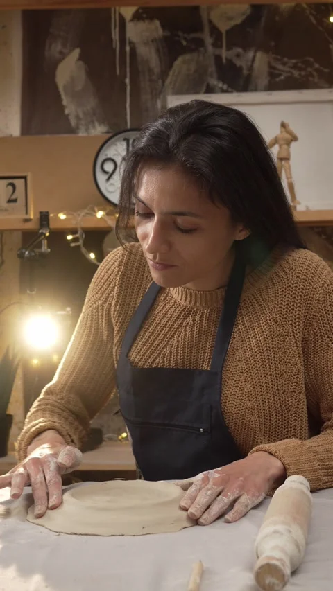 Craftswoman sits at her workspace table, gently molding and forming a clay .. Stock Footage 335881905
