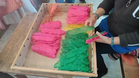 Craftswoman sorting colorful translucent leaf shaped crafts in a wooden tray Stock Footage 331550885