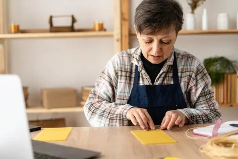 A craftswoman watching a video tutorial or training course on making wax ca.. Stock Photos