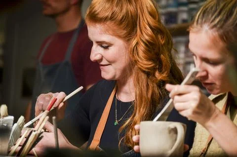 Craftswomen designing pottery using tools in workshop Stock Photos