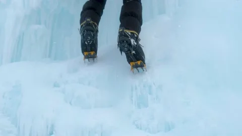 Crampons close-up on his feet ice climber on a frozen waterfall. Shards of ice. Stock Footage