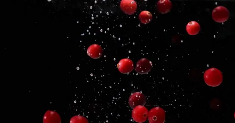 Cranberries fall down into clear water on black background Stock Footage 145715986