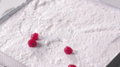 Cranberries fall on white cream. The process of making a cake. Stock Footage 157924593