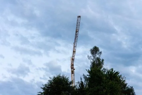 Crane among cloudy sky with tree at blue hour evening Stock Photos