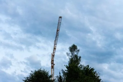 Crane among cloudy sky with tree at blue hour evening Stock Photos
