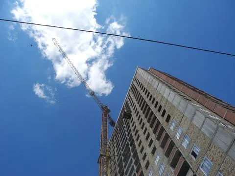 Crane and building under construction against blue sky Stock Photos