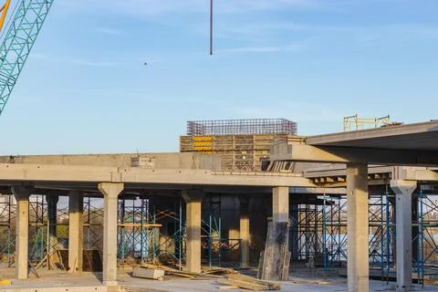 Crane and building under construction against blue sky on lake bank. Urban Stock Photos