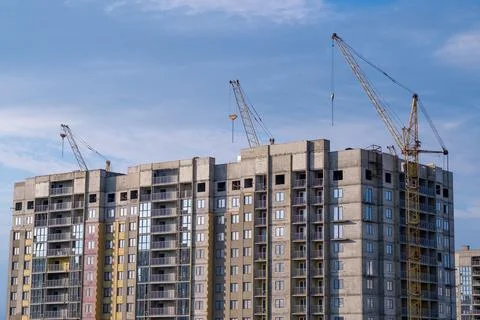 Crane and a building under construction against a blue sky background Stock Photos