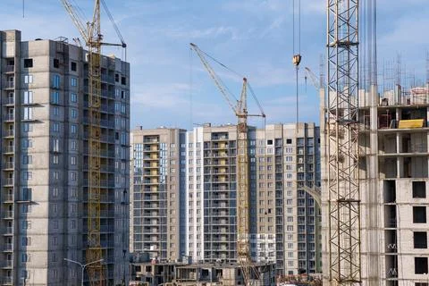 Crane and a building under construction against a blue sky background Stock Photos