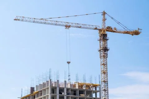 Crane and a building under construction against a blue sky background Stock Photos