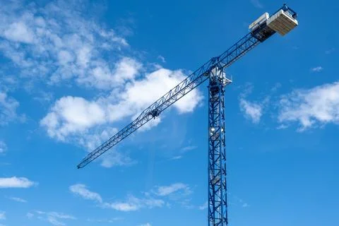 Crane and a building under construction against a blue sky background Stock Photos