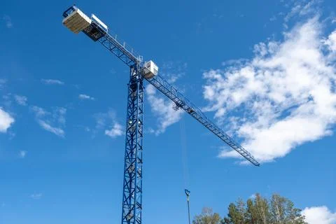 Crane and a building under construction against a blue sky background Stock Photos