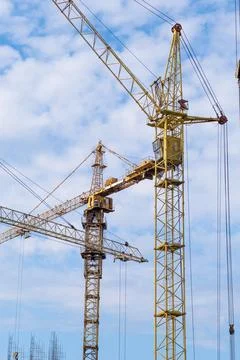 Crane and a building under construction against a blue sky background Stock Photos