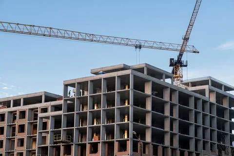 Crane and a building under construction against a blue sky background Stock Photos