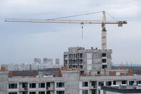 Crane and a building under construction against a blue sky background Stock Photos