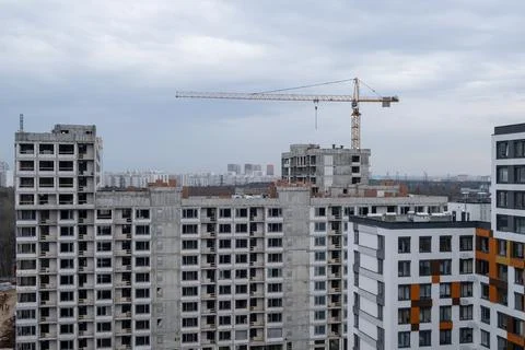 Crane and a building under construction against a blue sky background Stock Photos
