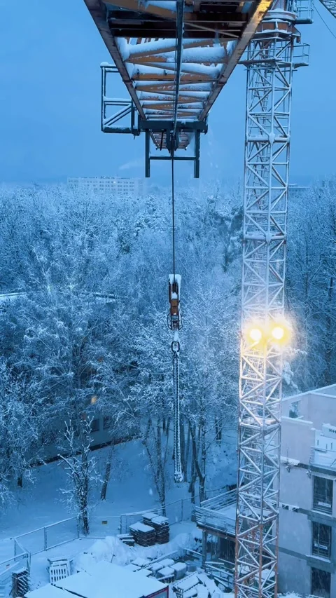 Crane Arm Moving Left as Snow Falls in Winter Construction Scene Stock Footage 307436859