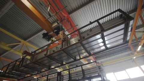 Crane beam moves stack of aluminum profiles in a factory warehouse. Heavy Stockfoto's