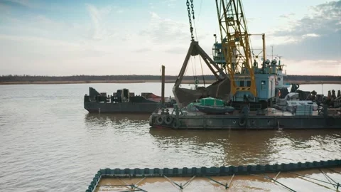 A crane bucket unloading sand from a barge to strengthen the shore by sheet Stock Footage 218404384