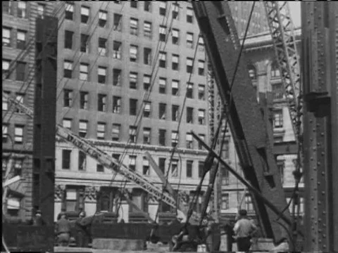 A crane, cables and construction workers lift a column into place during the Stock Footage 75273101