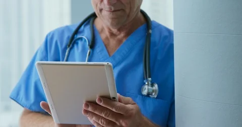Crane up from close up on tablet computer to medical doctor reading notes Stock-Footage 101032744