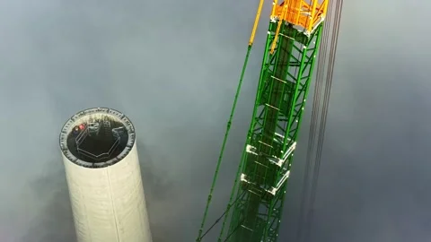 Crane Constructing a Huge Wind Turbine Tower in the Clouds, Aerial Parallax View Stock Footage 315260801