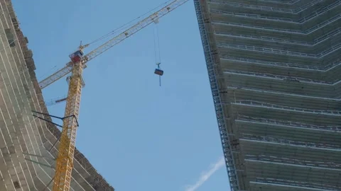 Crane on construction site lifting up construction materials up on the roof of Stock Footage 253222402