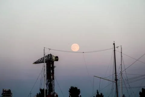 Crane at dusk with full moon visible behind in Amsterdam, the Netherlands Stock-Fotos