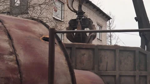 Crane grabber loading rusty scrap metal into the back of a truck for recycling. Stock-Footage 145991544