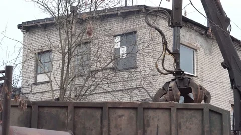 Crane grabber loading rusty scrap metal into the back of a truck for recycling. Stock Footage 145991777