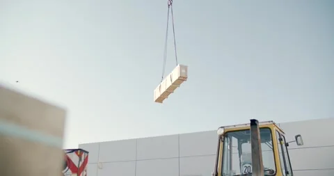 Crane hoisting a wrapped building material load against a, construction Video stock 342512733