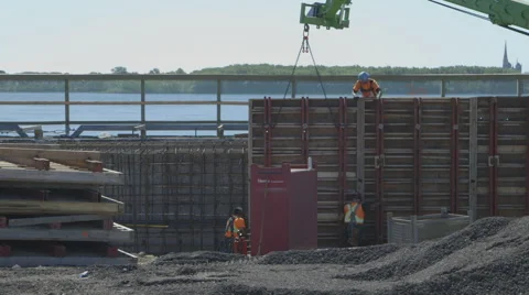 Crane holding concrete wall while construction workers instal it Video stock 65052566
